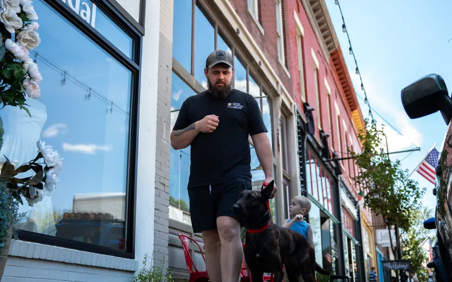 A dog heeling past storefronts downtown, advanced obedience around distractions
